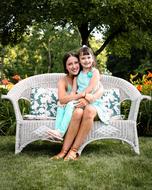 mom and daughter sit on the garden couch