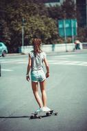Girl skateboarding on the photoshoot on the beach, near the colorful plants