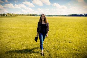 a girl walks across a field with green grass