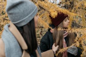 Beautiful mother with the daughter in warm clothing, among the colorful plants, in the autumn