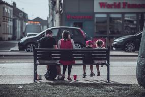 couple with children on a bench on a city street