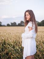 pregnant girl in a white dress on a wheat field