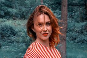 portrait of a redhead woman in a green forest