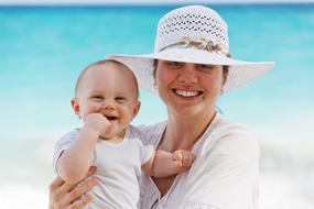 happy mom with baby on the beach on blurred background