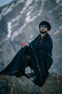 a man with a beard sitting on a rock