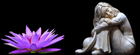 statuette of a girl and a lotus flower on a black background