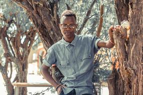 portrait of a man with glasses near a tree in africa