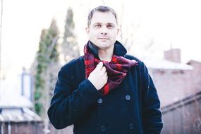 a man in a black coat with a red-purple scarf