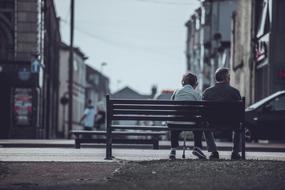 a couple of pensioners sitting on a bench in the street