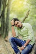 Bearded man with wrist watch and bracelets, posing among the colorful plants