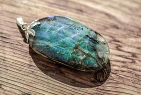 Close-up of the beautiful and colorful, shiny labradorite, with the ring, on the wooden surface, in light