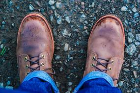 Close-up of the person's legs wearing brown boots and jeans