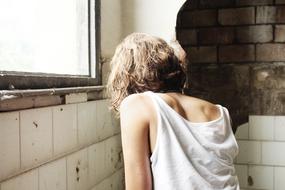 Girl posing among the walls with window with light