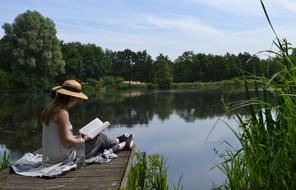 Reading book on Lake pier at Summer