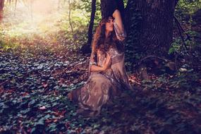 girl posing under a tree in a dark forest