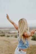 blonde woman with wide sweep of arms in a field in a blurred background
