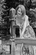 Black and white photo of the woman washing hands in water, in the village