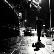 man walks away on pavement in city, black and white