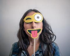 Woman, holding colorful emoji mask, in light