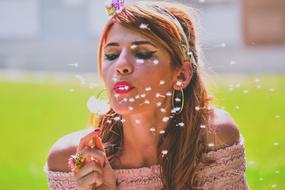 portrait of a girl blowing dandelion in the meadow on a blurred background