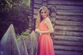 beautiful girl in a red suit near a wooden house