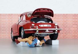 Model of the mechanic repairing shiny, red "Porsche 356" car near the wall