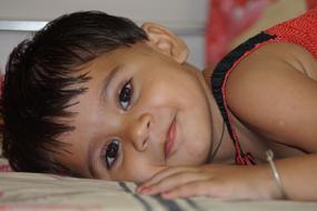 Portrait of the cute girl child, laying on the bed
