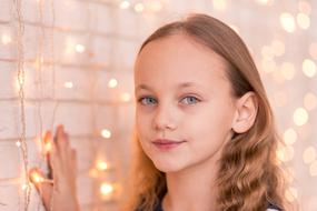 little girl posing near the wall with a garland