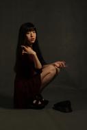 Asian woman with make-up, sitting in light, among the darkness