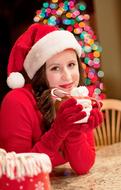 girl dressed as santa claus with a cup of cocoa in her hands