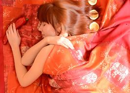 young Woman sleeps on red bed with pepper in hand