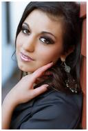 beautiful brunette posing by the wall of the house