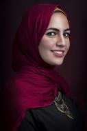 Portrait of the smiling woman in colorful hijab, at black background