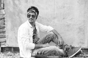 black and white, stylish guy sits against the wall