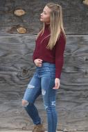 Blonde girl in jeans, posing near the wooden barn