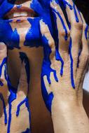 Blue paint on female face and hands