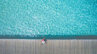 woman in wide hat walking on pathway at sea, top view