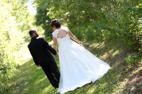 Wedding couple, Bride and Groom walking holding hands in park