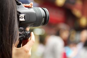 professional photo camera in the hands of a girl on a blurred background