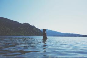 Woman stands in water at scenic coastline