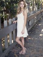 blonde in a white dress at a wooden fence