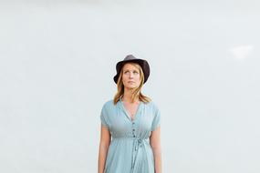Portrait of the blonde woman, in turquoise dress, with the hat, at white background