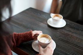 cup of Coffee in female hands on table