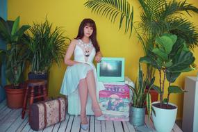 Portrait of the woman in turquoise dress, sitting among the green plants