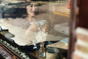 woman with a cup of coffee outside the restaurant window