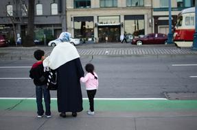 Woman with the children, standing on the street with cars