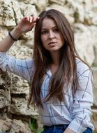 Portrait of the beautiful girl in shirt, posing near the stone wall