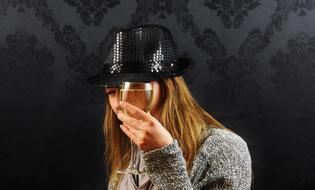 woman in black hat with glass of white wine