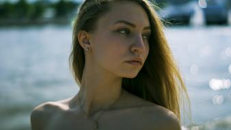 young girl with earrings and a chain on the background of the lake