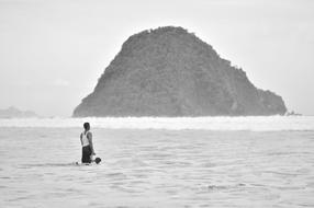 Silhouette of a person with the child, on the water, near the beautiful island